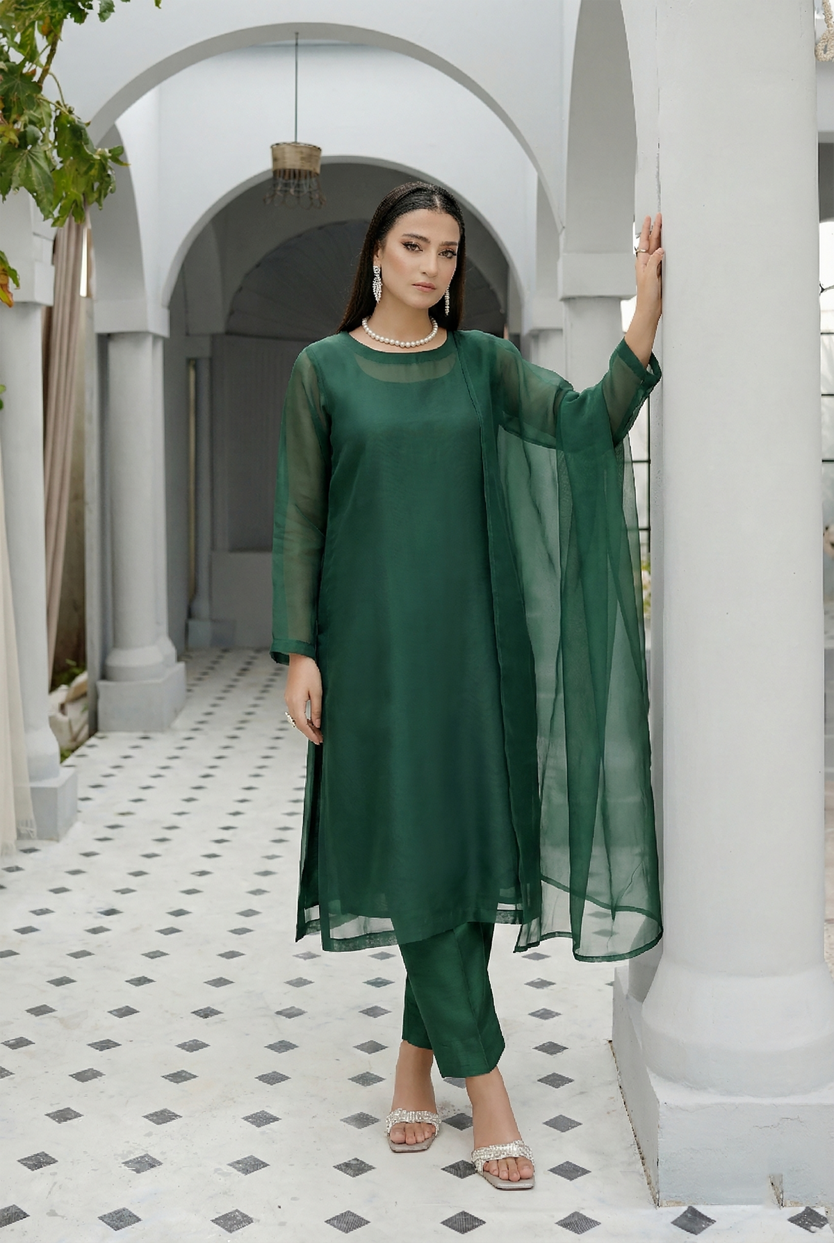 ROZAIB Forest Green luxury organza stitched suit for women. This premium ready to wear stitched dress features a unique suspended-yoke architecture with a floating vertical structure and master-tailored seamless finish. A minimalist 3-piece stitched suit in a rich forest green earthy tone, paired with raw silk relaxed trousers and a matching airy organza dupatta. Designed for a calm, authoritative executive look with zero embroidery.