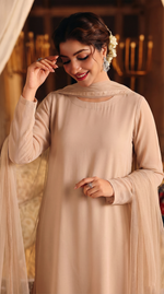 ROZAIB Nude Sand minimal festive stitched suit in premium flowy chiffon fabric. This luxury ready to wear stitched dress features a straight relaxed flow fit with ultra-fine micro chiffon grain and master-tailored vertical lines. A 3-piece stitched suit for women designed for effortless elegance, paired with raw silk cigarette trousers and a lightweight Bareeze net dupatta. Perfect for a sophisticated minimalist look in any season.