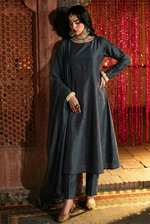 ROZAIB Deep Charcoal executive A-line stitched suit in premium raw silk fabric. This luxury ready to wear stitched dress features a sophisticated structured silhouette with authentic raw silk slub texture. A minimalist 3-piece stitched suit for women, designed for an authoritative and professional look, paired with straight cigarette pants and a matching fluid chiffon dupatta. Ideal for office wear and formal festive gatherings.