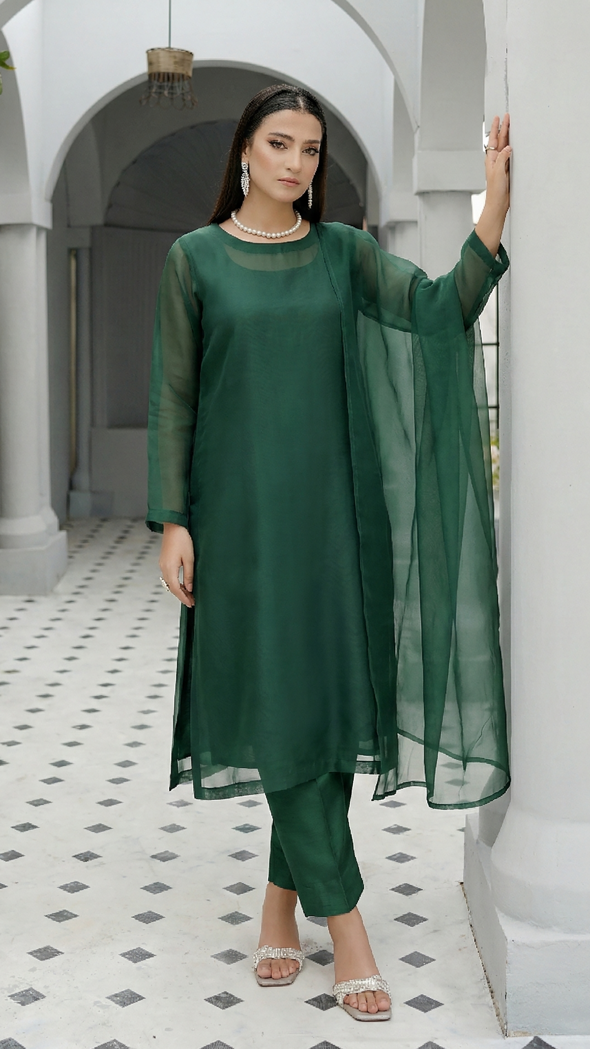 ROZAIB Forest Green luxury organza stitched suit for women. This premium ready to wear stitched dress features a unique suspended-yoke architecture with a floating vertical structure and master-tailored seamless finish. A minimalist 3-piece stitched suit in a rich forest green earthy tone, paired with raw silk relaxed trousers and a matching airy organza dupatta. Designed for a calm, authoritative executive look with zero embroidery.