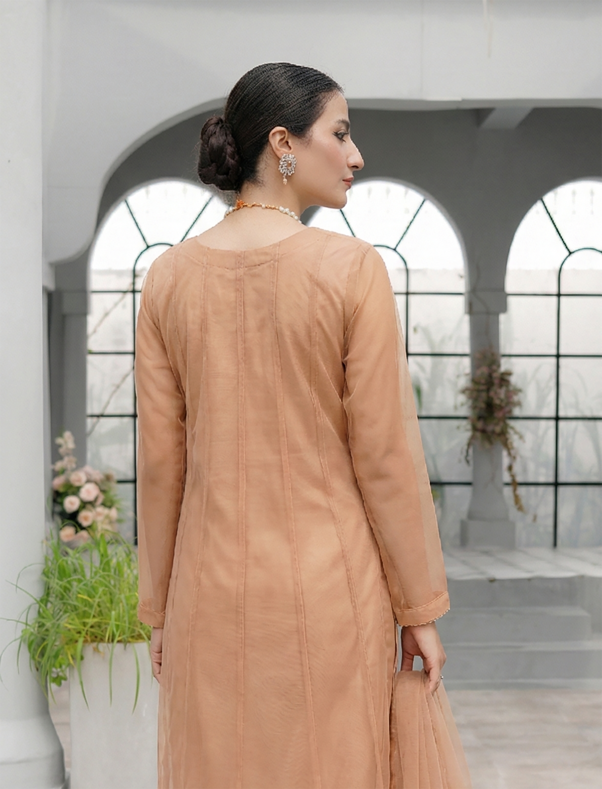ROZAIB Champagne Peach luxury Bareeze net minimal kalidaar stitched suit. This premium ready to wear stitched dress features a 12-kali graceful flow fit, ultra-fine 0.3mm micro-mesh texture, and master-tailored vertical kali joints. A minimalist 3-piece stitched suit for women in a warm champagne-peach tone, paired with raw silk cigarette trousers and an airy Bareeze net dupatta. Designed for a traditional yet modern festive look with zero embroidery.