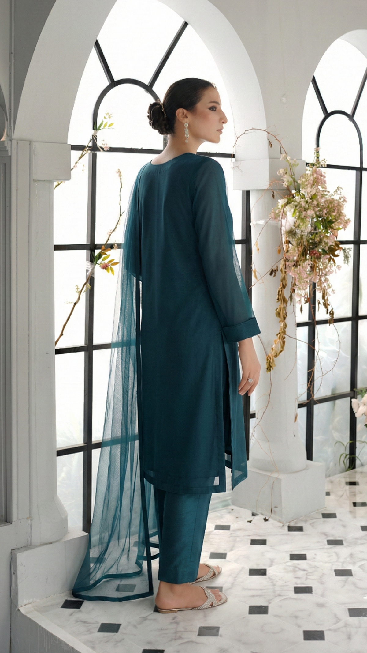 ROZAIB Teal Blue luxury solid organza stitched suit for women. This premium ready to wear stitched dress features a seamless front panel with architectural structured tailoring and a clean matte finish. A minimalist 3-piece stitched suit in a rich teal blue jewel tone, paired with raw silk straight trousers and a matching solid organza dupatta. Designed for a powerful, uninterrupted executive look with zero embroidery.