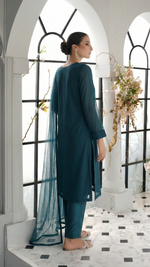 ROZAIB Teal Blue luxury solid organza stitched suit for women. This premium ready to wear stitched dress features a seamless front panel with architectural structured tailoring and a clean matte finish. A minimalist 3-piece stitched suit in a rich teal blue jewel tone, paired with raw silk straight trousers and a matching solid organza dupatta. Designed for a powerful, uninterrupted executive look with zero embroidery.