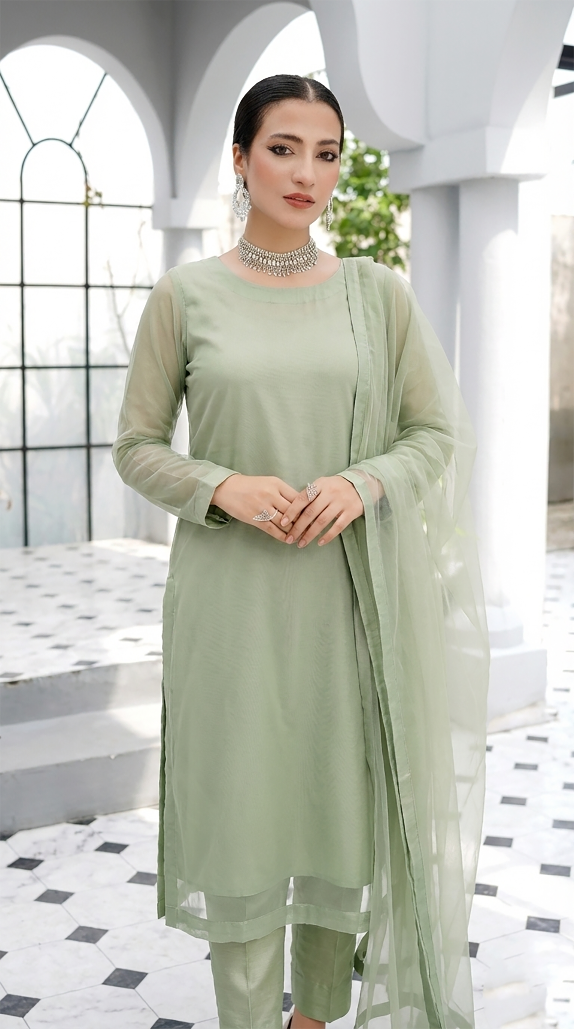 ROZAIB Sage Pista luxury Bareeze net long straight kurta stitched suit. This premium ready to wear stitched dress features a clean plain construction, ultra-fine 0.3mm micro-mesh net texture, and master-tailored vertical fall. A minimalist 3-piece stitched suit for women in a soft muted pistachio green tone, paired with raw silk cigarette trousers and an airy Bareeze net dupatta. Designed for a fresh, sophisticated festive look with zero embroidery and precision stitching.